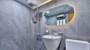 A modern bathroom with grey tiles, a white sink, a toilet, and a shower with a glass door. - NO25 HOTEL BUPYEONG (Incheon)