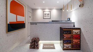 A hotel reception area with a modern design, including a reception desk, a welcome mat, and a wall-mounted clock. - NO25 HOTEL BUPYEONG (Incheon)