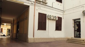 Un edificio con fachada blanca, dos contraventanas marrones y una puerta visible.