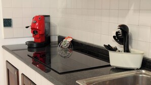 Una encimera de cocina con una cafetera, un estante para especias y un organizador de utensilios.