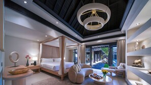 A modern hotel room with a four-poster bed, a sitting area with a sofa and armchairs, a coffee table with flowers, and a view of a pool and garden. - Des Indes II by Elite Havens (Kabupaten Badung)
