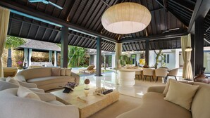 Un'ampia area interna con soffitto alto, un tavolo centrale grande e posti a sedere.