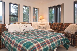 A bedroom with a large bed, a sofa, and multiple windows. - Mountain living, over 1400 sqft condo in Blueberry Hills, exceptional outdoor space, book for Summer (Whistler)