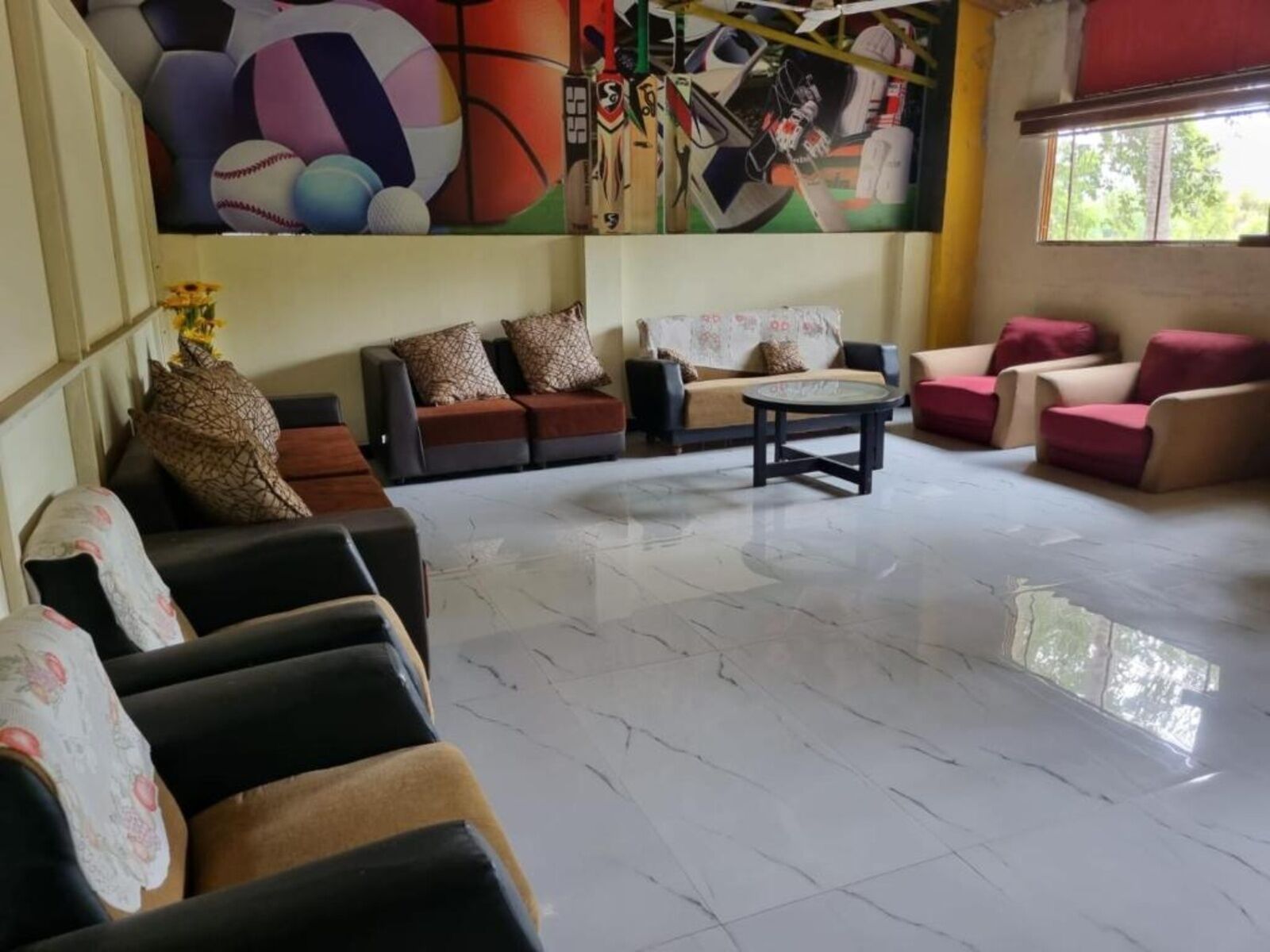 A spacious room with a large mural, multiple seating areas, and a large window.