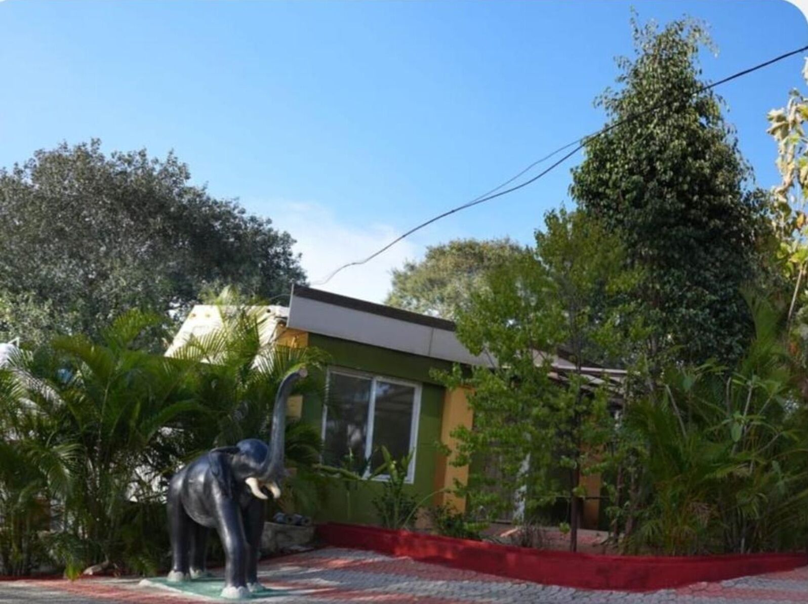 A building with a green facade, a red border, and a statue of an elephant.