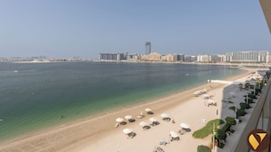 A beach with clear waters and a cityscape in the background. - Vogue| Grand Blue Beachfront Designed By Elie Saab (Dubai)
