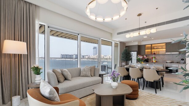 A modern living room with a sofa, coffee table, and dining area. - Vogue| Grand Blue Beachfront Designed By Elie Saab (Dubai)