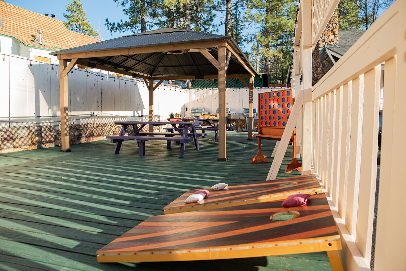 A wooden deck with picnic tables and a shuffleboard table.