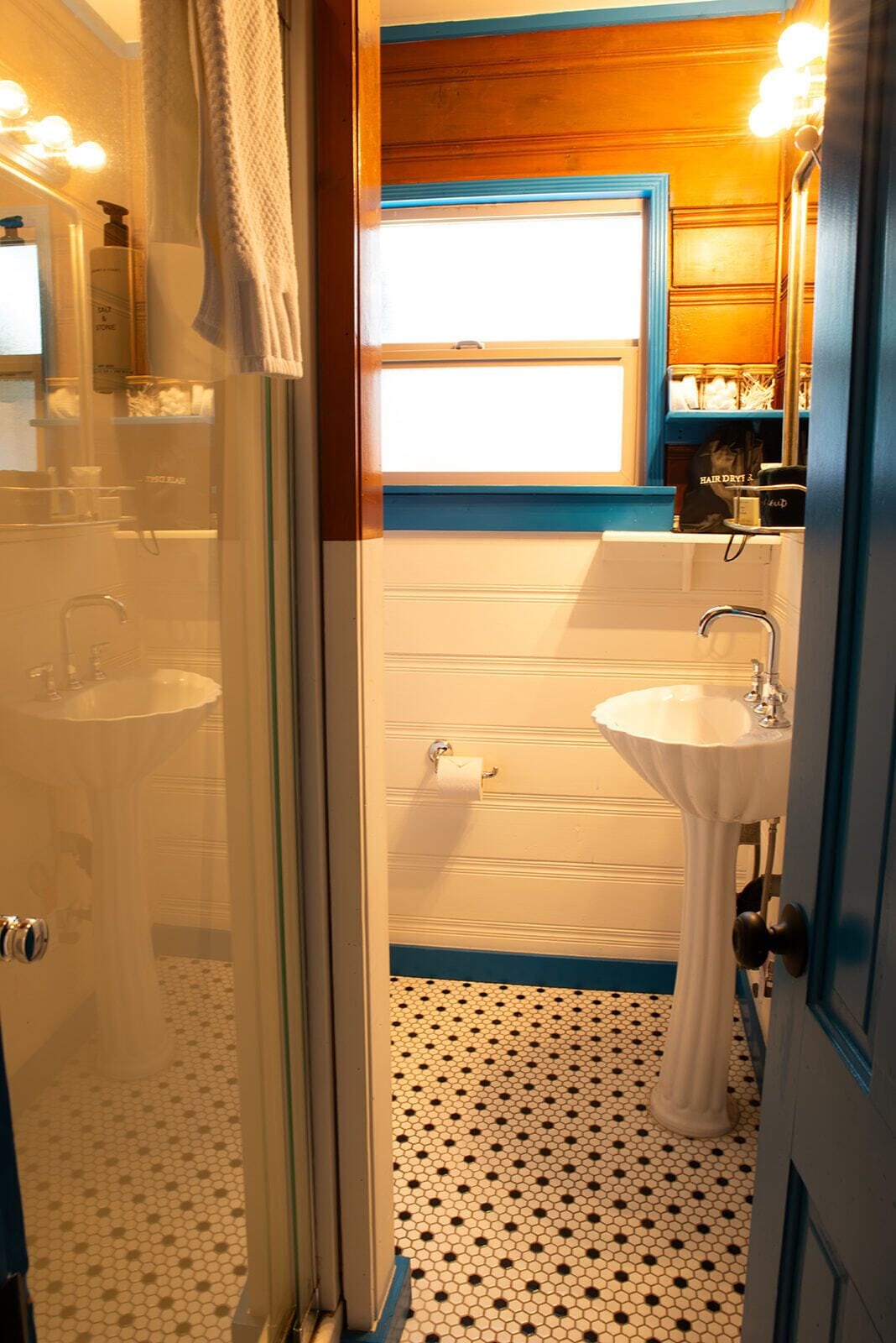 Un baño con lavamanos blanco, un espejo y zona de ducha.