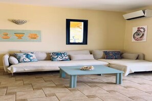 A living room with a beige sofa, a blue coffee table, and artwork on the walls. - Casa Anna Maria luxury villa near the sea (Heraklion)