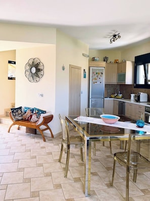 Une cuisine moderne équipée d’un réfrigérateur, d’un four à micro-ondes et d’un évier. On y trouve également un coin repas avec une table et des chaises en verre.