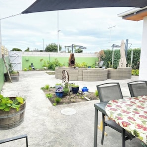 Une terrasse extérieure avec une table et des chaises, un pot en osier et un mur végétal.