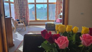 Et værelse med et spisebord dækket til et måltid, en sofa og udsigt gennem et stort vindue.