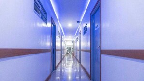 Un pasillo largo y estrecho con puertas a ambos lados, que conduce a una habitación luminosa al final.