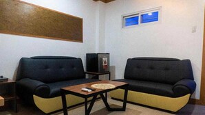 Una sala pequeña con dos sofás, una mesita de centro y un televisor.