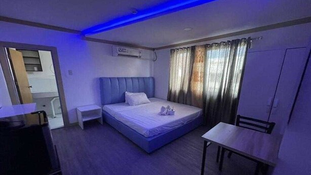 Una habitación de hotel con una cama individual, una mesita de noche, un escritorio y un armario.