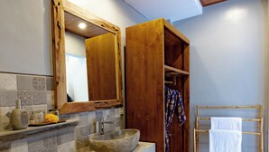 A bathroom with a stone sink, wooden vanity, and a mirror above it. - Poset Unique Inn (Ubud)
