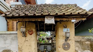 A traditional entrance with a tiled roof, two stone lion statues, and a small shrine with a lantern. - Poset Unique Inn (Ubud)