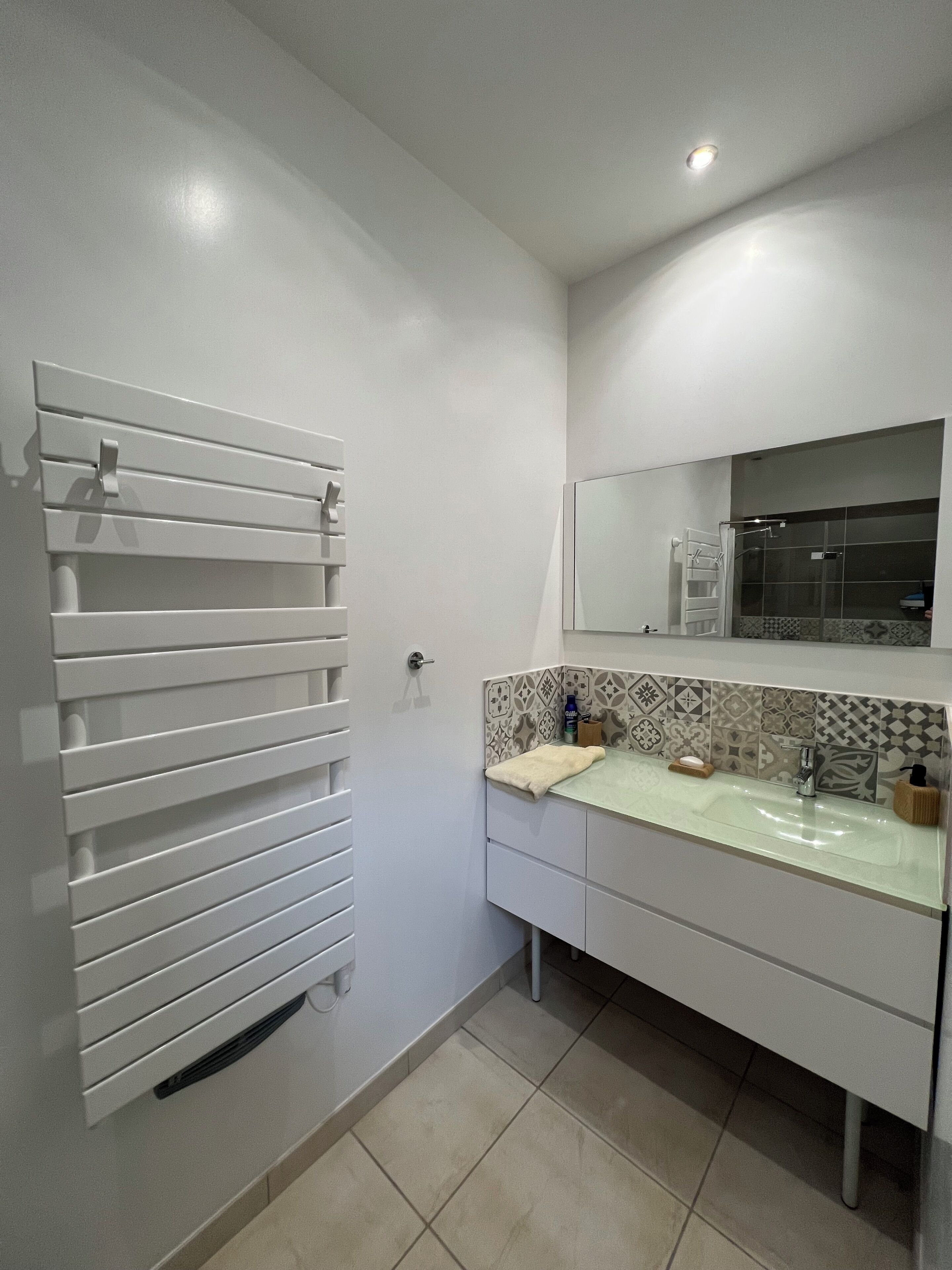 A bathroom with a white vanity, a towel rack, and a shower area.