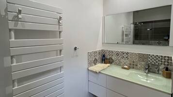 A bathroom with a white vanity, a towel rack, and a shower area.