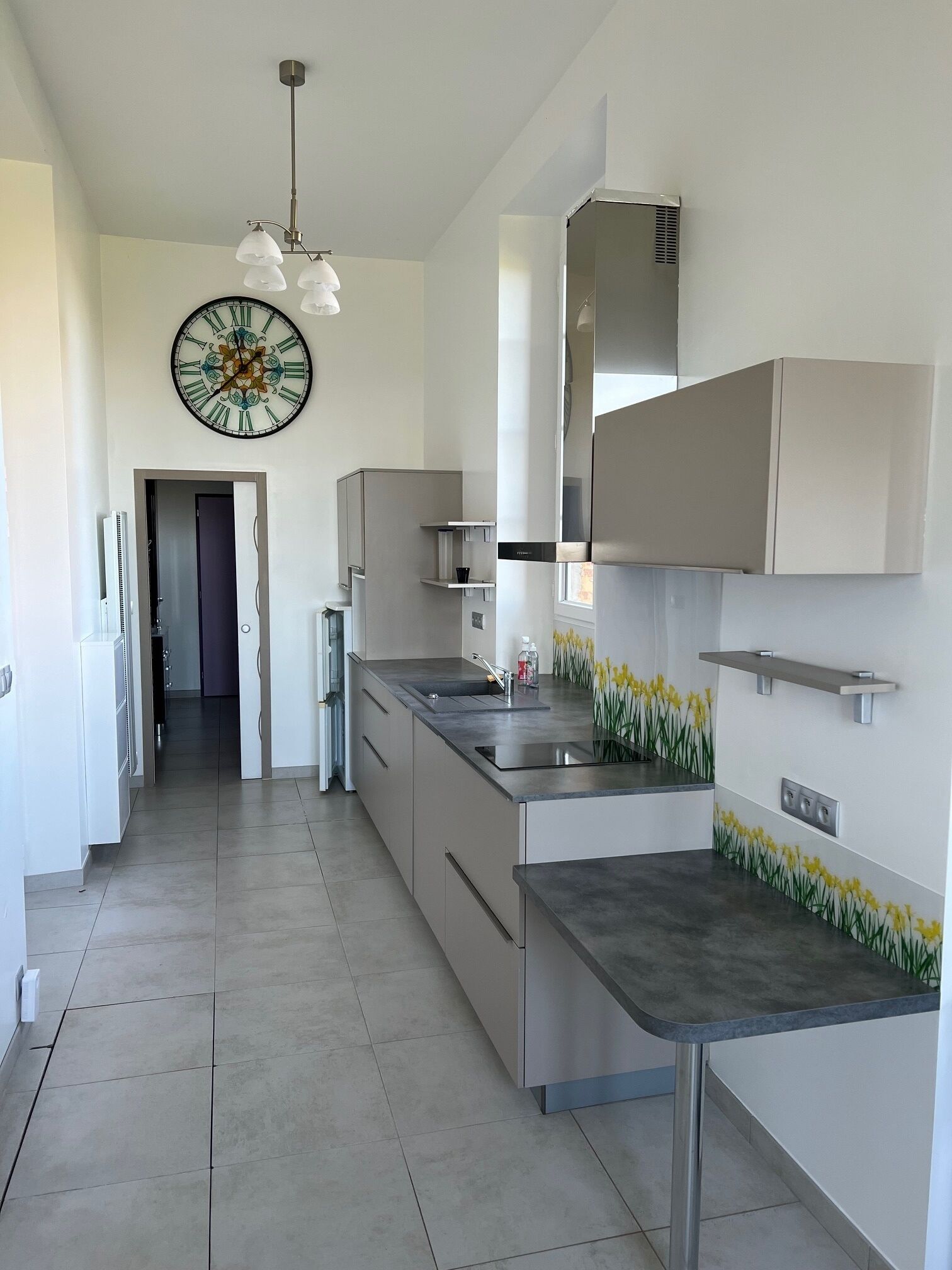 A modern kitchen with a central island, stainless steel appliances, and a decorative clock.