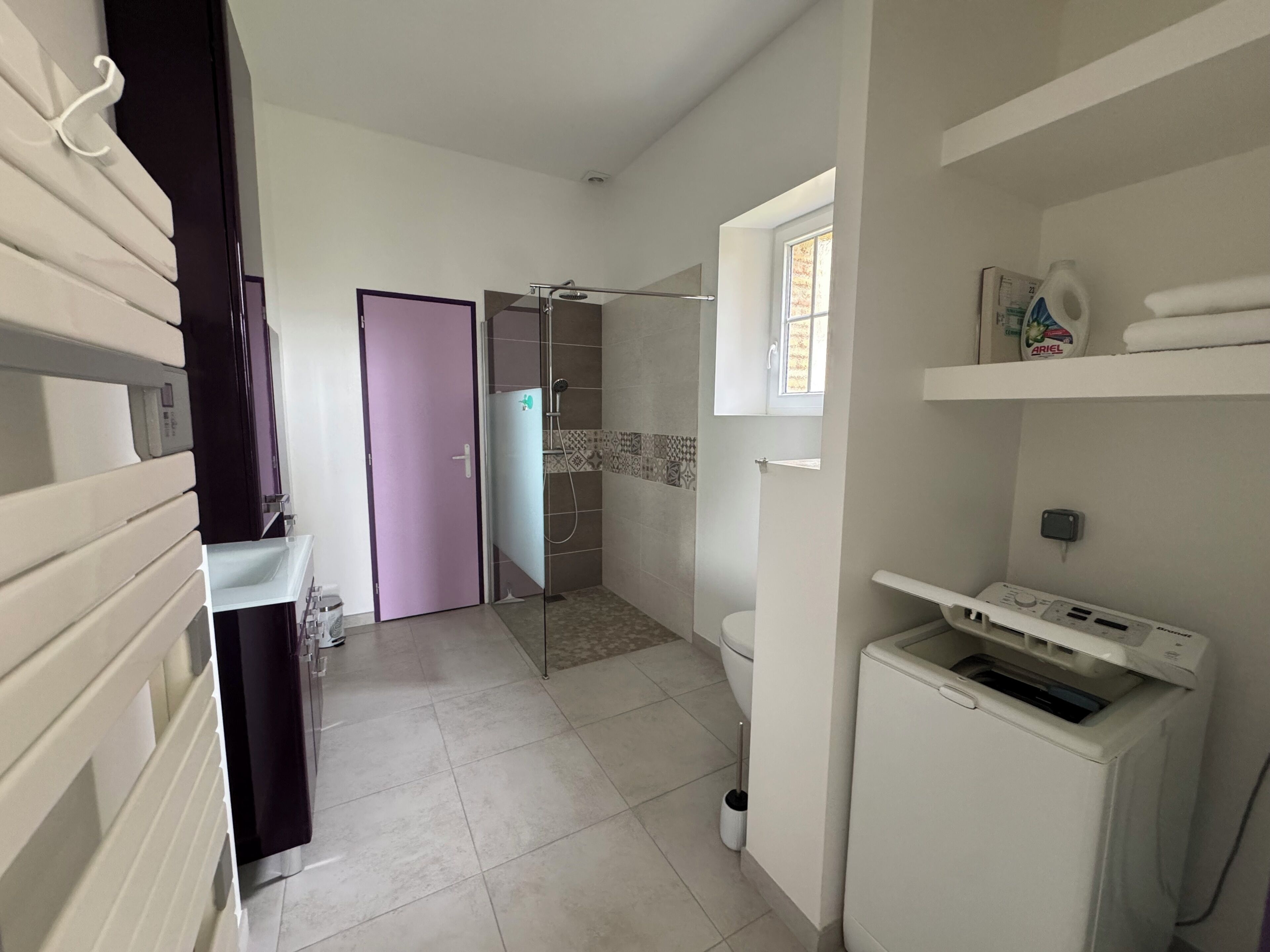 A bathroom with a shower, toilet, and a washing machine.