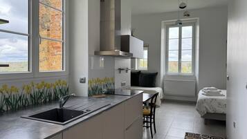 A modern kitchen with a large window, a built-in stove, and a dining area with a chair.