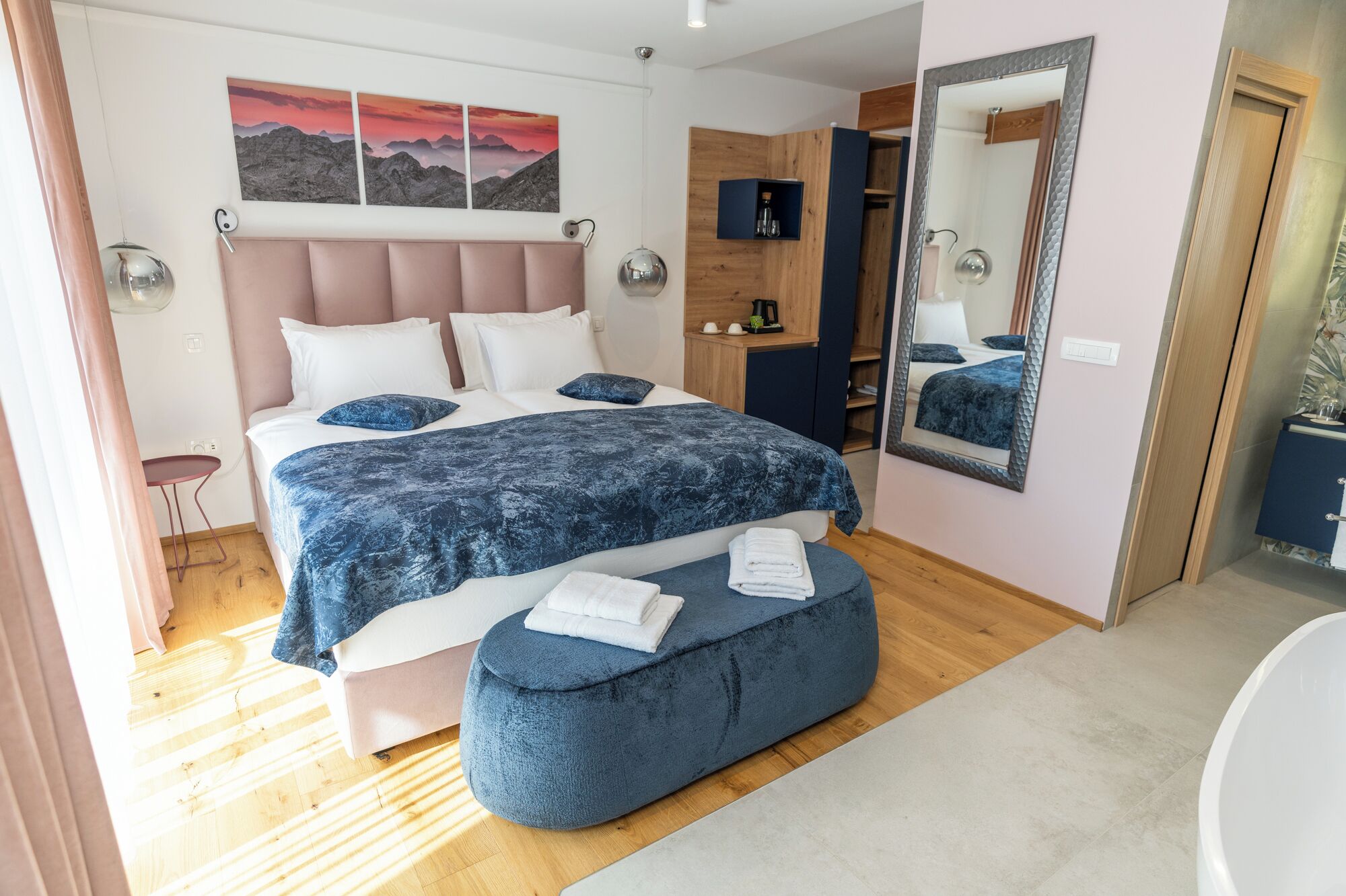 Een moderne slaapkamer met een groot bed, een nachtkastje, een spiegel en uitzicht op de badkamer.