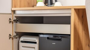 A compact kitchen with a built-in refrigerator and a dishwasher, wooden cabinetry, and a coffee maker on the countertop. - Landhouse Bled (Bled)