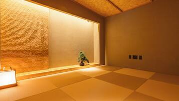 A tatami mat room with a shoji screen, a small bonsai tree, and a traditional Japanese-style lamp.