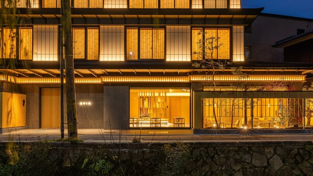 Un bâtiment moderne doté de grandes fenêtres et d’un mur en pierre à l’avant.