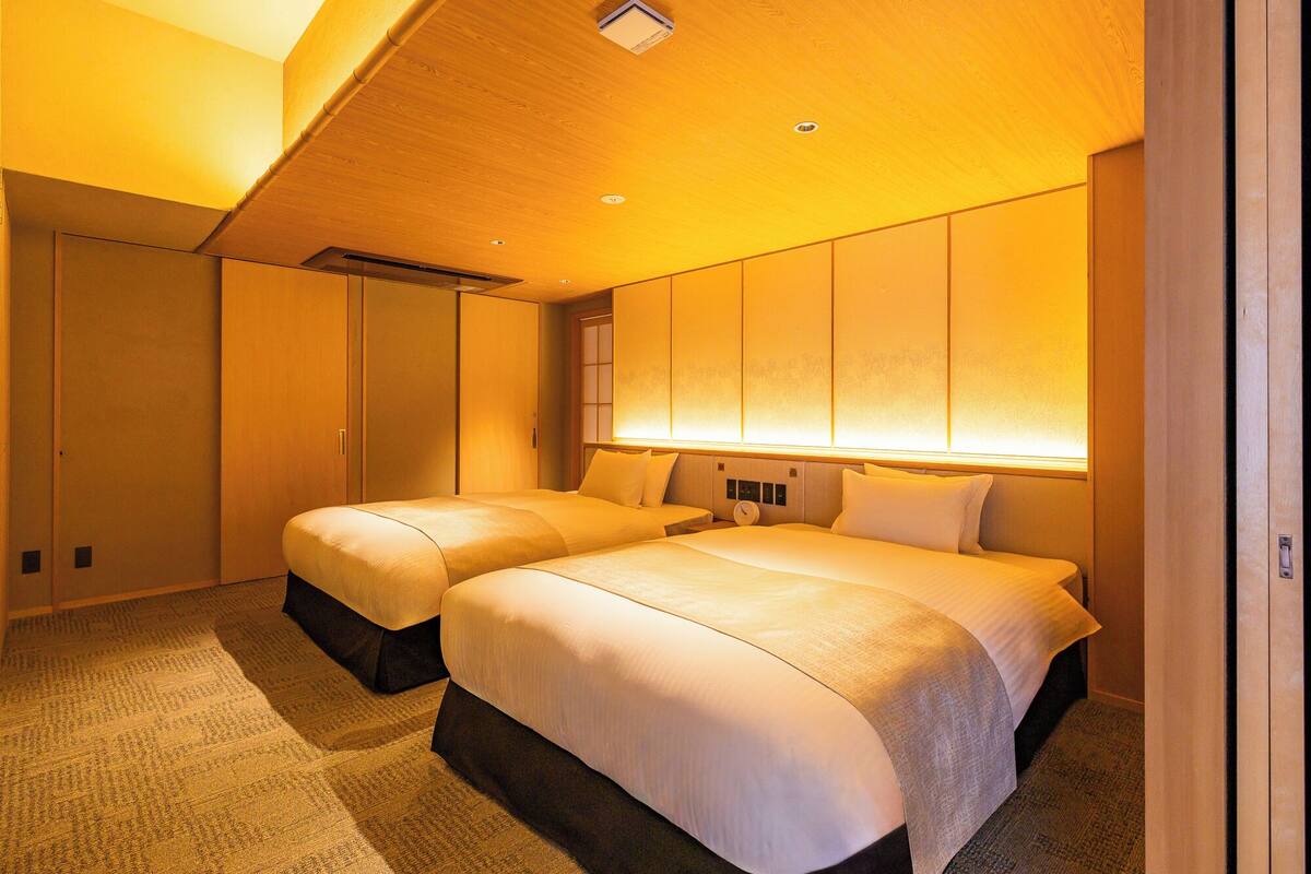 Une chambre d’hôtel avec deux lits, une grande armoire et un plafond doté d’un éclairage encastré.