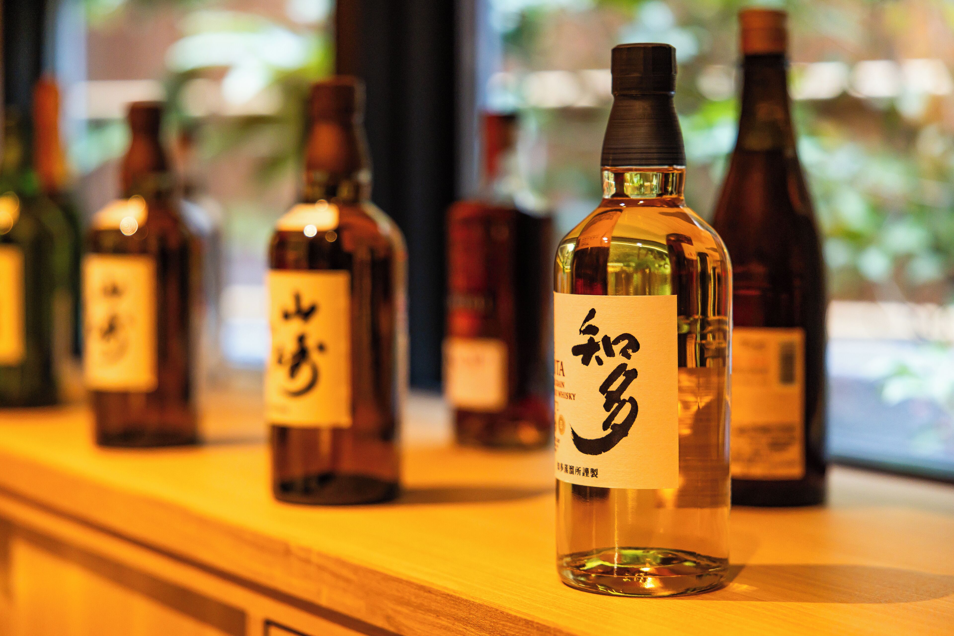 A row of bottles with labels on a wooden surface.