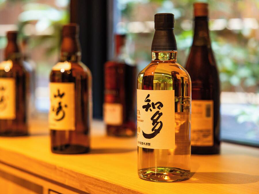 A row of bottles with labels on a wooden surface.