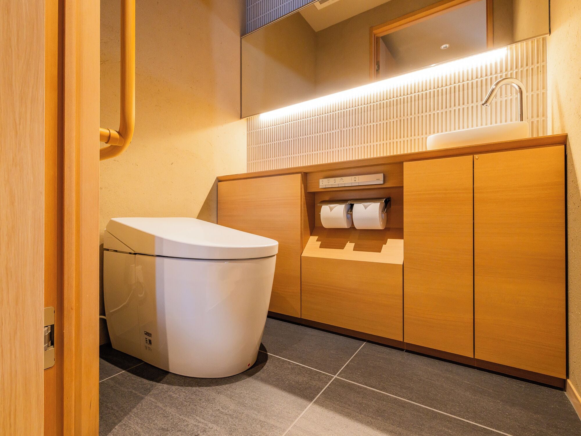 A modern bathroom with a toilet, a sink, and a toilet paper holder.