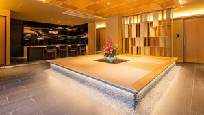 Un hall d’hôtel moderne comprenant un comptoir d’accueil, un espace salon et un mur décoratif agrémenté d’un luminaire.