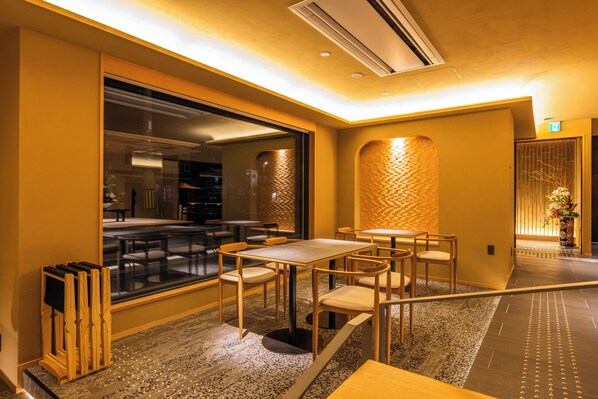 Un espace repas moderne, avec des tables et des chaises, une grande fenêtre et un mur à texture.