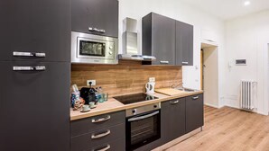 Una cocina moderna con armarios oscuros, encimera de madera, horno empotrado y microondas.