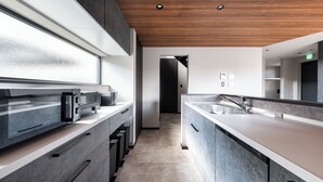 A modern kitchen with a wooden ceiling, a large window, and a built-in oven. - JANUS villa Furano (Furano)