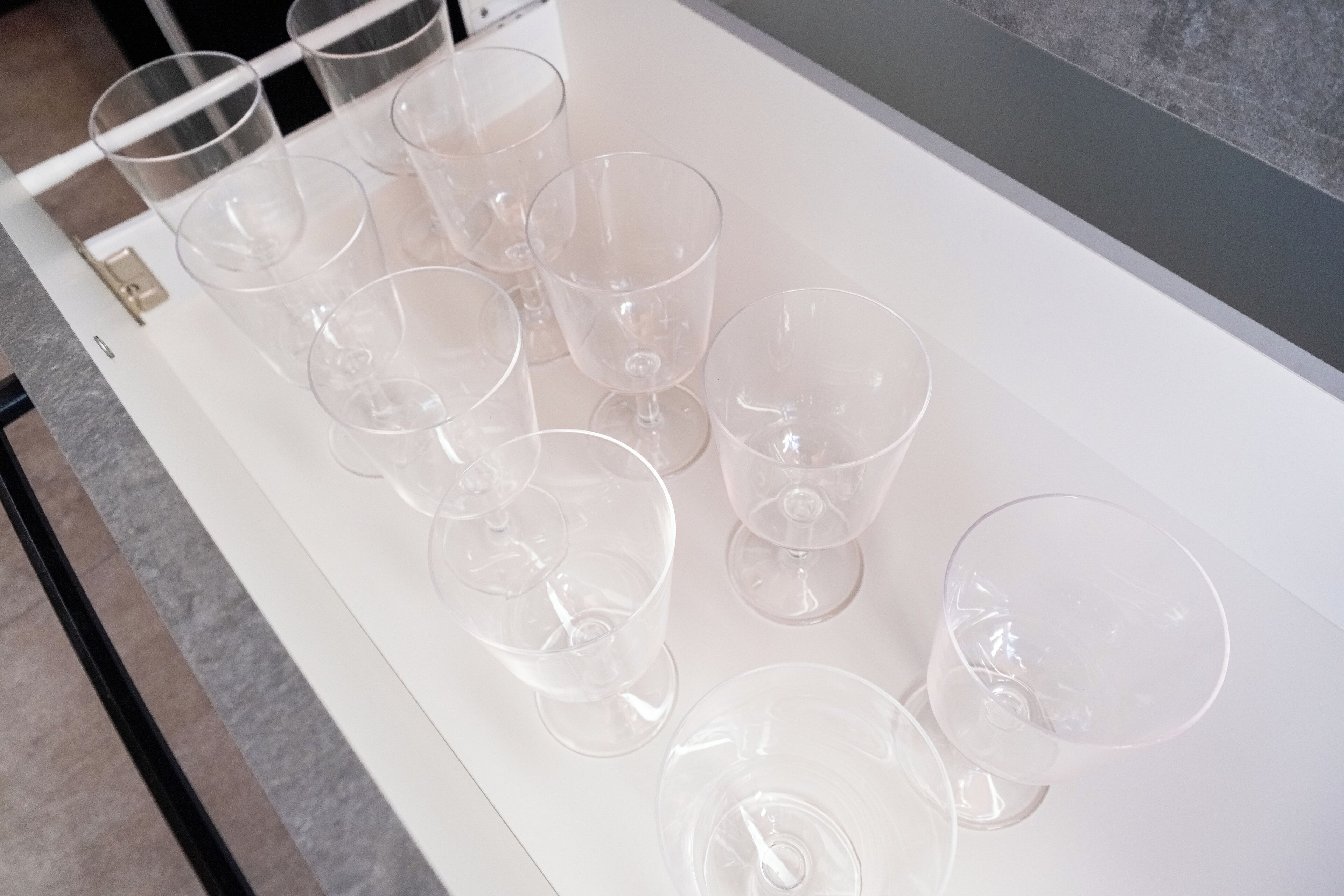 A white tray with several empty wine glasses arranged on it.