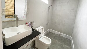 Une salle de bain équipée d’un lavabo, d’un miroir, de toilettes et d’une douche.