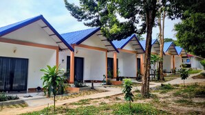A row of modern, single-story buildings with blue roofs and orange walls, surrounded by greenery and a well-maintained garden. - Koh Rong Lagoon Bar And Restaurant  (Koh Rong)