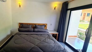 Une chambre avec un grand lit, deux lampes de chevet et une vue sur l’extérieur grâce à une porte coulissante.