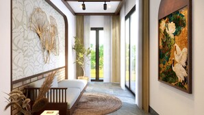 Een moderne hotellobby met een bank, een rond tapijt, een groot schilderij en een decoratieve wand.