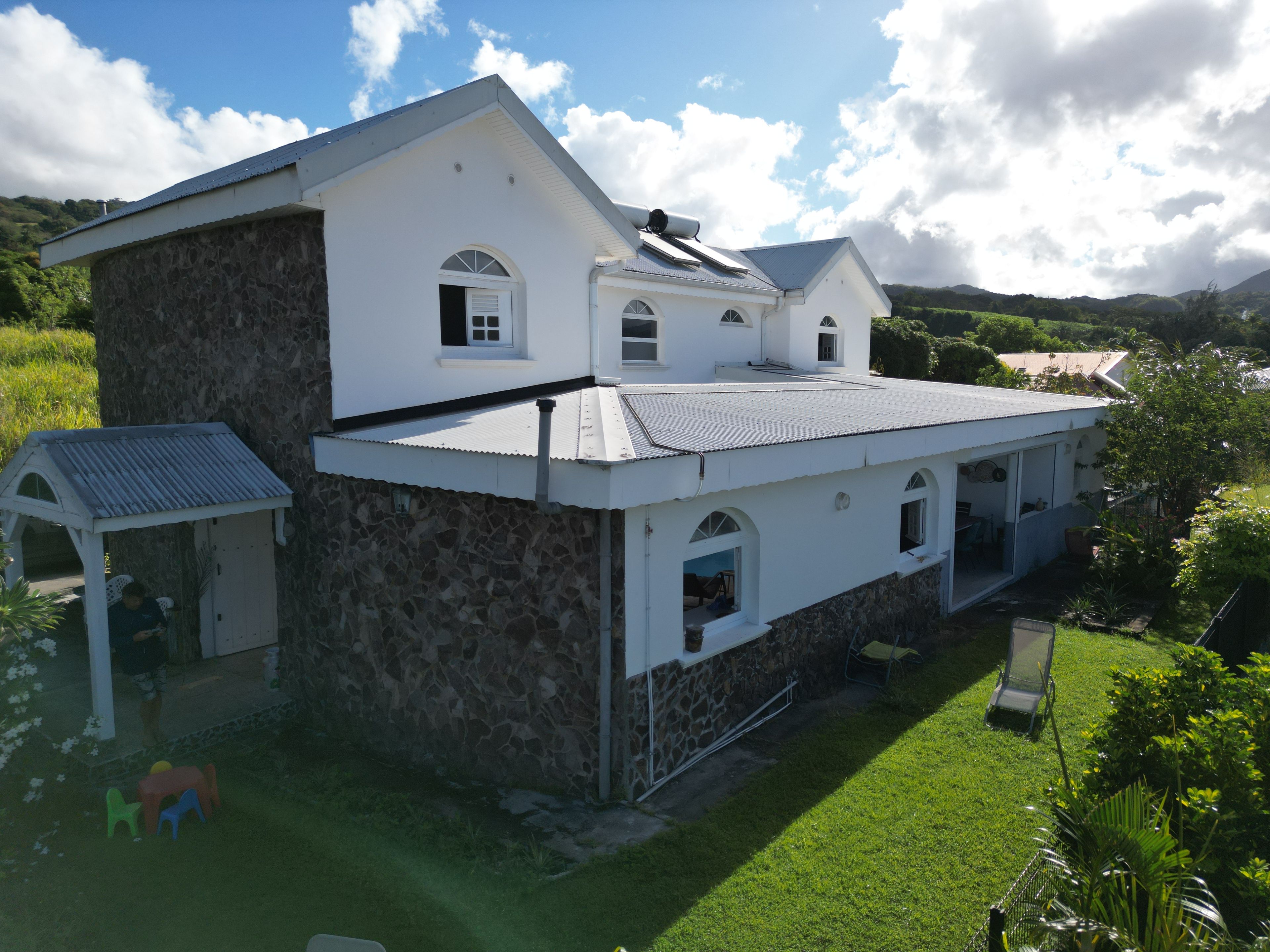 Une maison à deux étages avec une façade en pierre, un porche couvert et une pelouse bien entretenue.