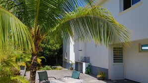 A patio with a table and chairs, surrounded by palm trees and potted plants. - L'Hacienda (Saint-Pierre)