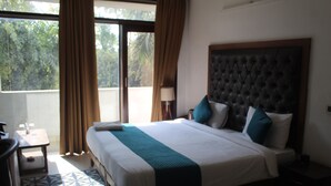 Une chambre d’hôtel avec un grand lit, un bureau et une fenêtre avec des rideaux.