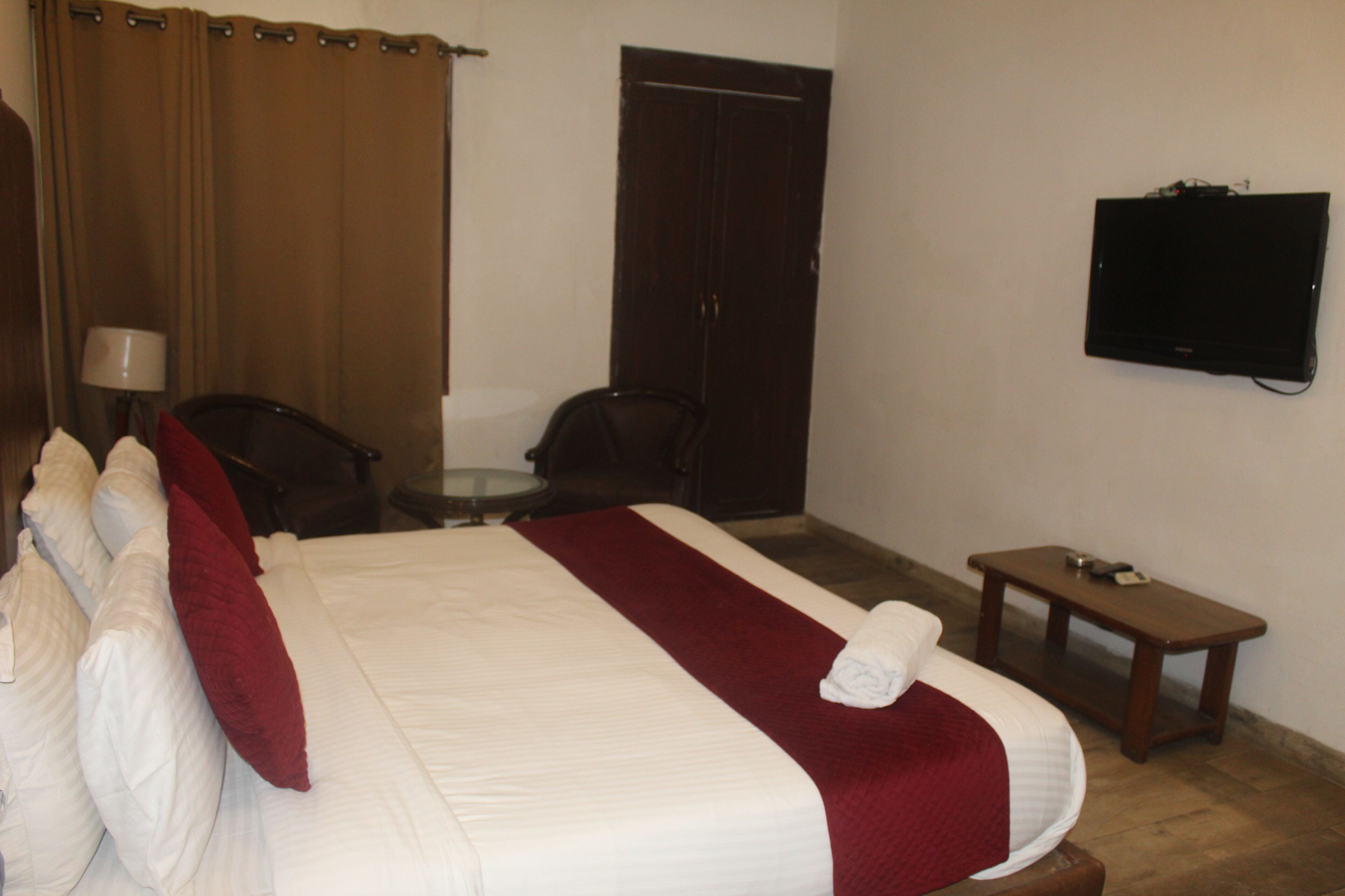 A hotel room with a bed, a TV mounted on the wall, a desk, and a chair.