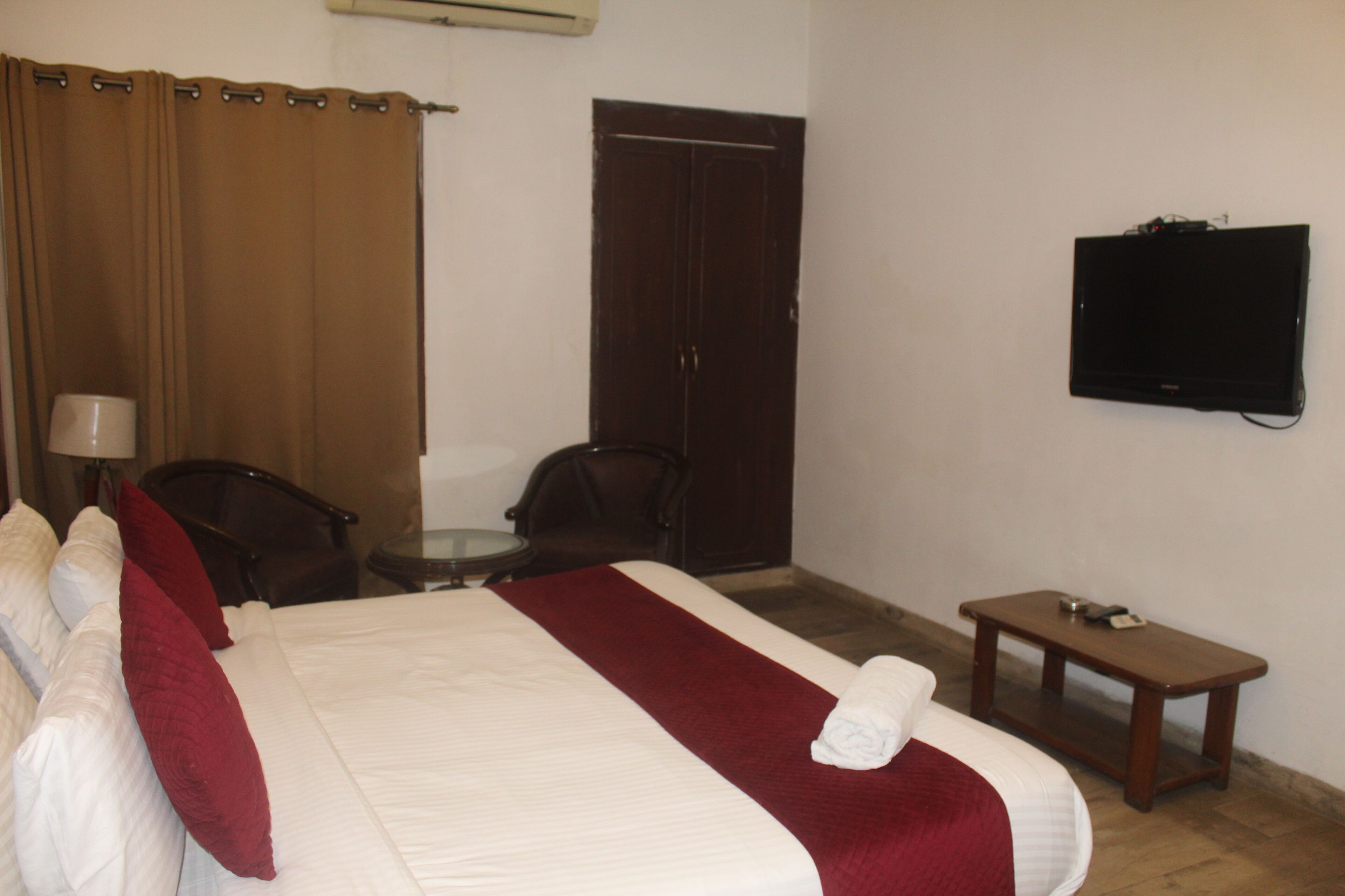 A hotel room with a bed, a TV, a desk, and a chair.