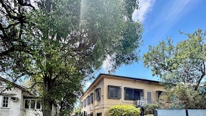 A two-story house with a front yard, a wooden fence, and a metal gate. - Studio Room Ensuite Bathroom with Separate Entrance (Woolloongabba)